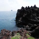 Stromboli, coulée de lave atteignant la mer avec en fond, une île constituée par une ancienne colonne de lave