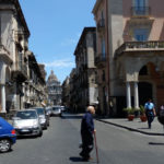 Catane, un viel homme traverse une rue avec le Duomo en fond
