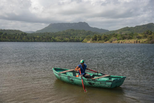 Région de Baracoa, barque devant la silhouette massive d'El Yunque, l’enclume de Christophe Colomb